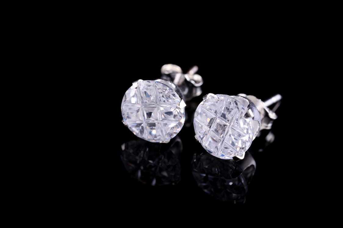 Pair of silver diamond stud earrings on a black background